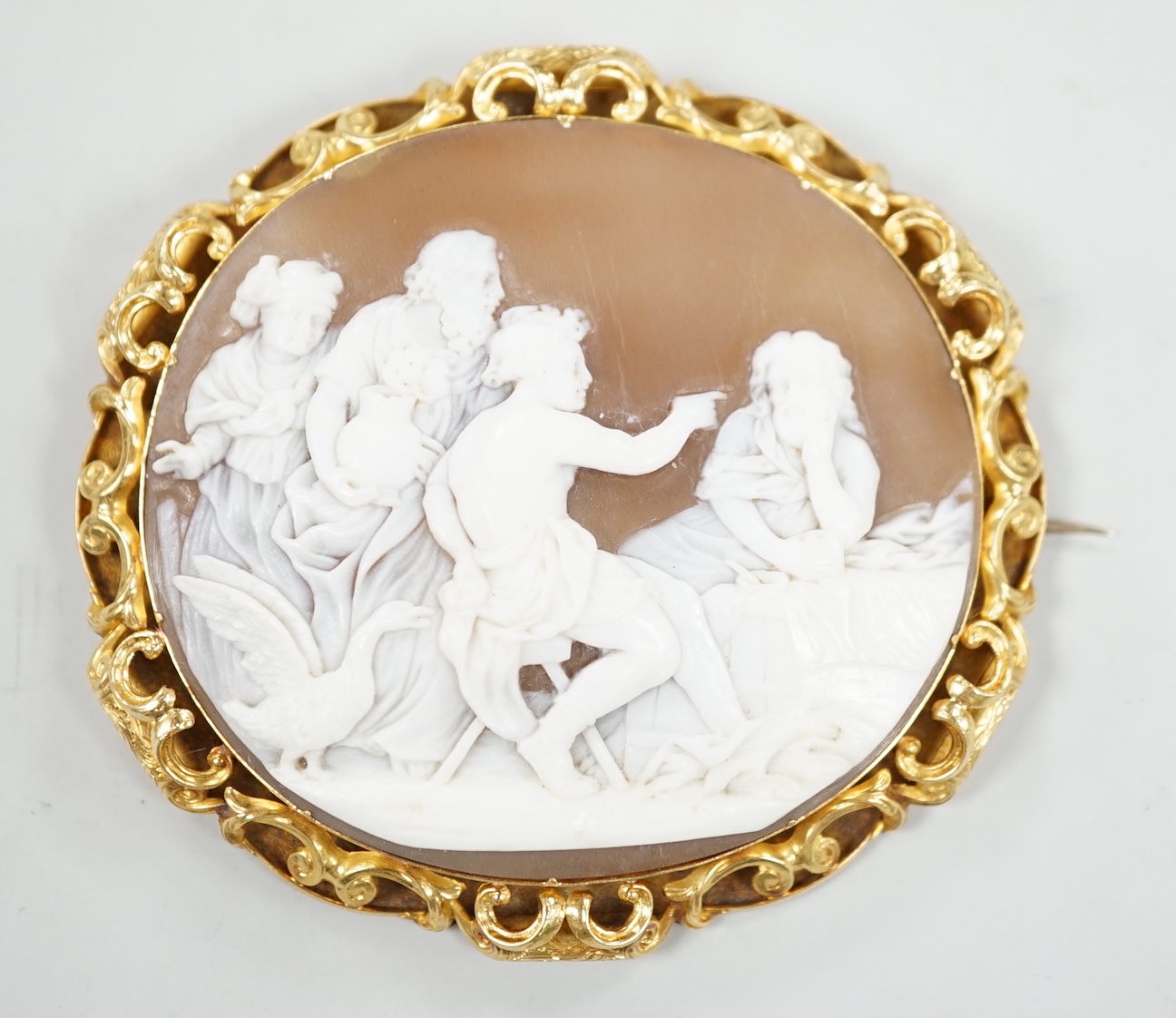 A Victorian yellow metal mounted oval cameo shell brooch, carved with classical figures, width 64mm, gross weight 26.8 grams (pin clasp a.f.).